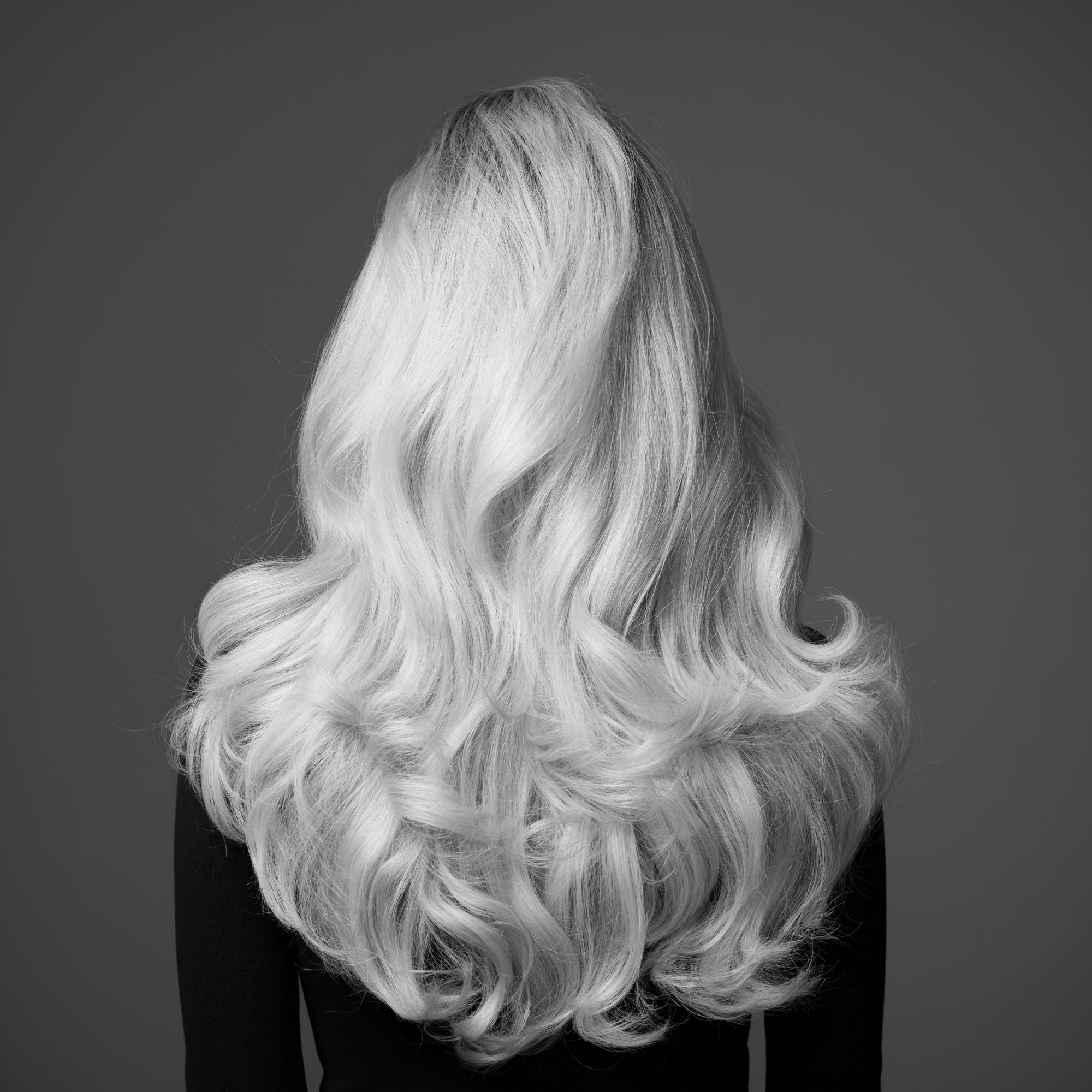 a beautiful monochromatic shot of back of a woman's head with long flowing hair after weft extensions in West Palm Beach